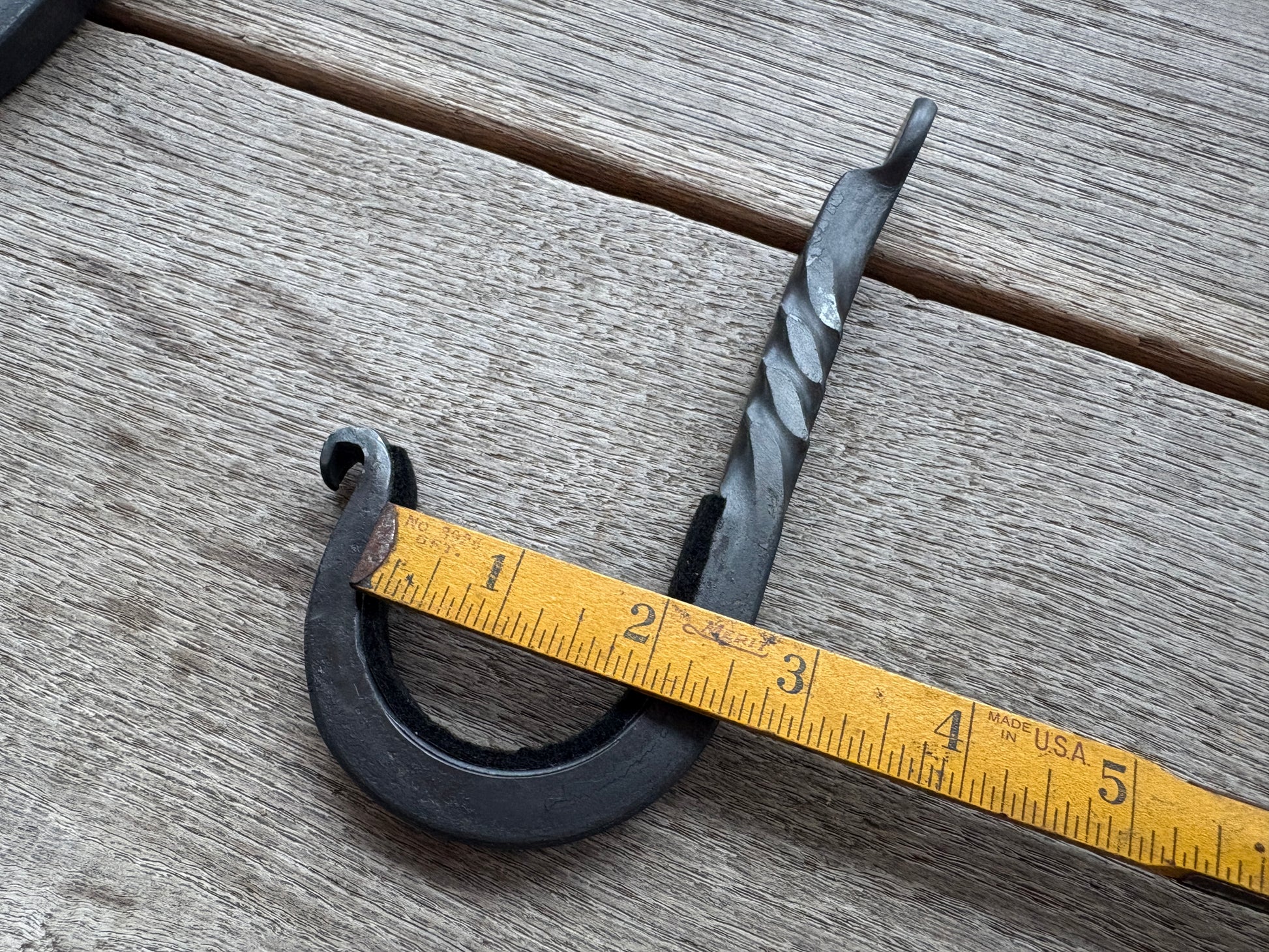 gun hook with ruler showing that it can hold a rifle two inches wide