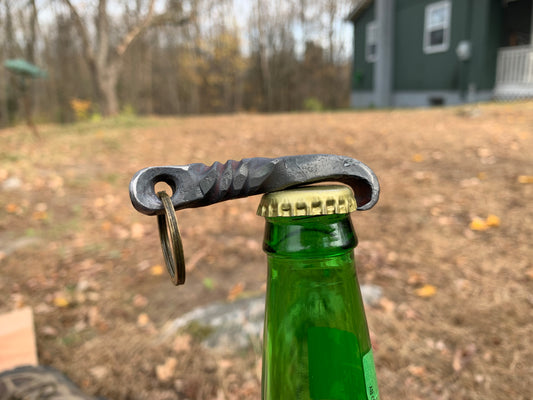 Hand forged iron bottle opener on top of beer bottle